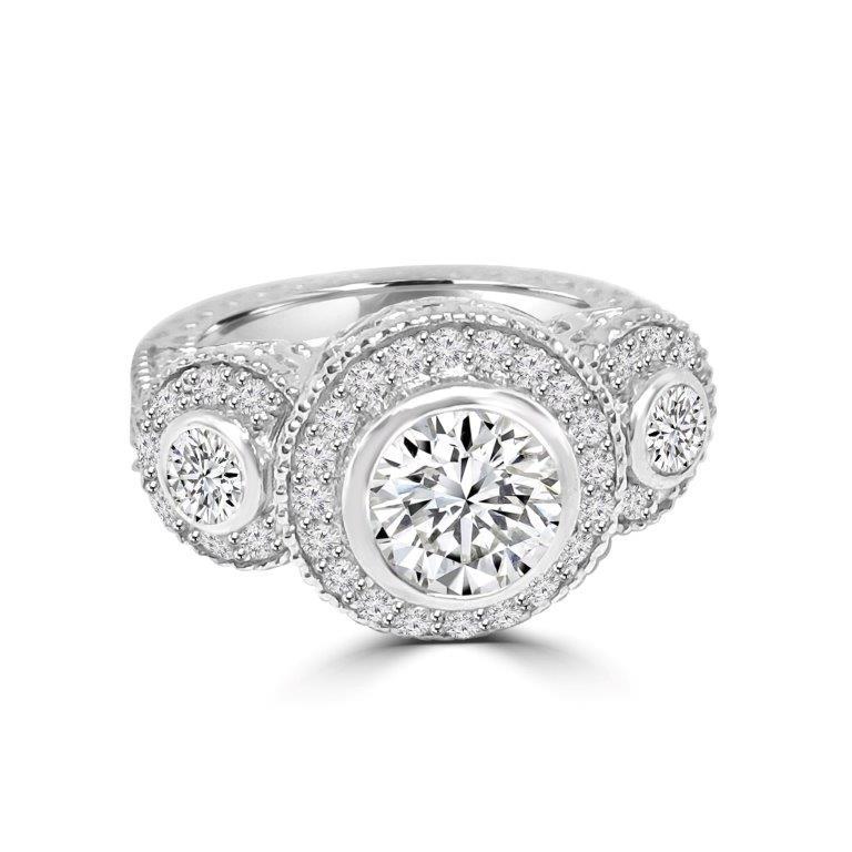 The DiamondVeneer Fashion Three Stones Cubic Zirconia Engagement Ring 635R13665 features three round stones in halo settings with sparkling accents and intricate band detailing.
