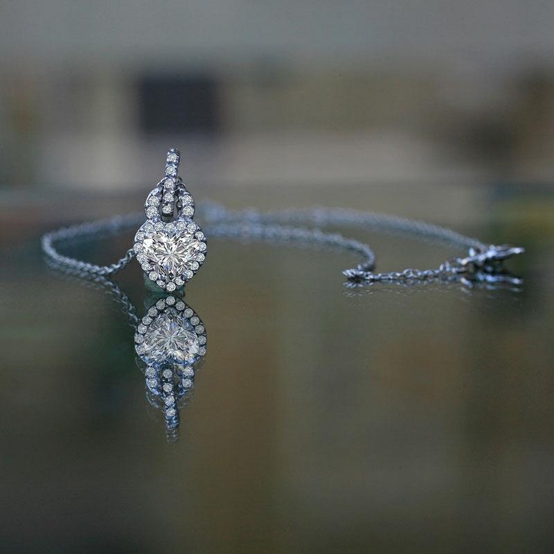The DiamondVeneer Fashion 1CT Heart Diamond Veneer Cubic Zirconia Pendant (635P10779A) features a heart-shaped cubic zirconia set on a delicate chain, sparkling elegantly as it rests on a reflective surface.