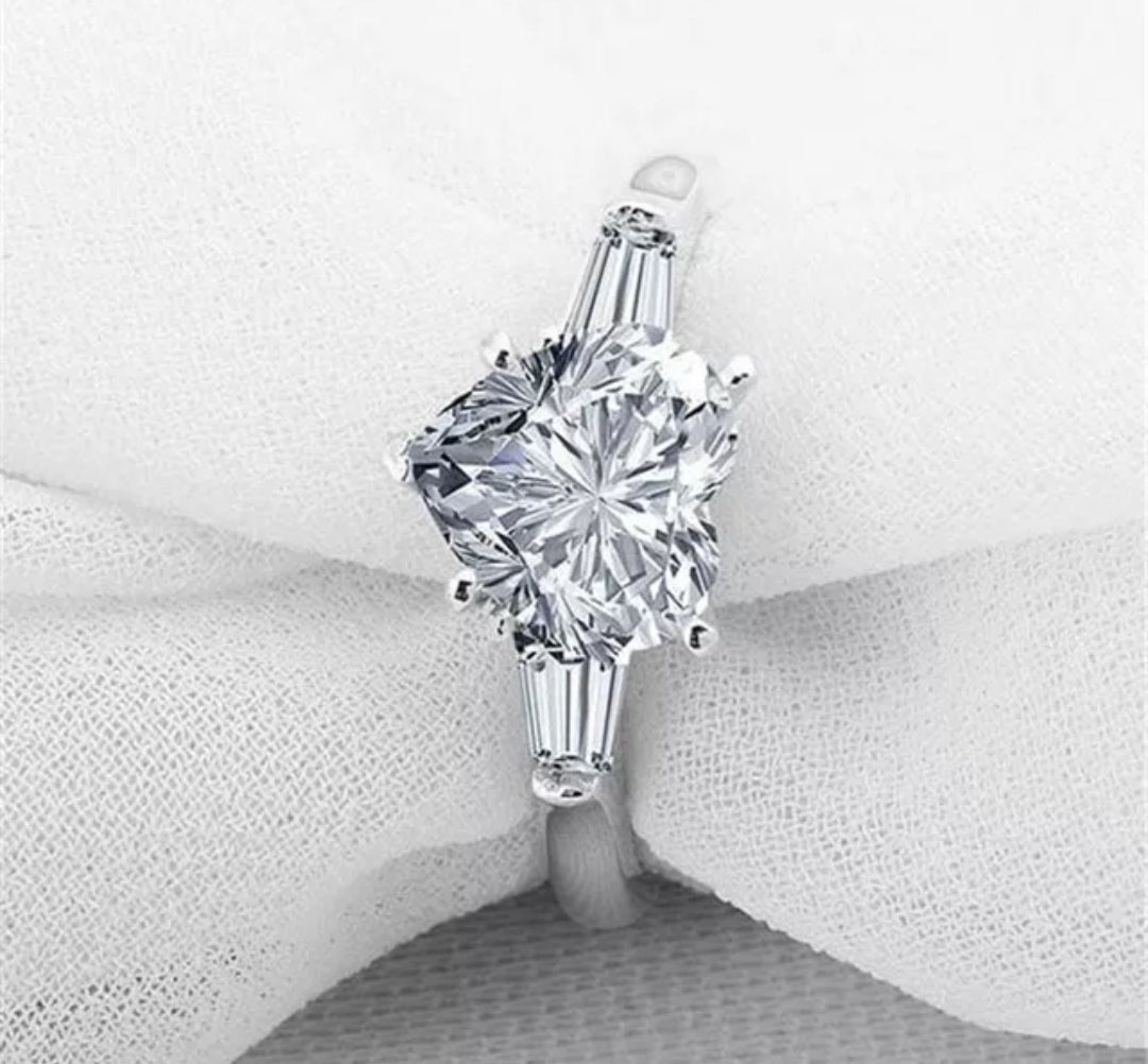 The DiamondVeneer Fashion 5CT Heart Cubic Zirconia Ring (635R71352) features a stunning heart-shaped center stone and is displayed on a soft white fabric background.