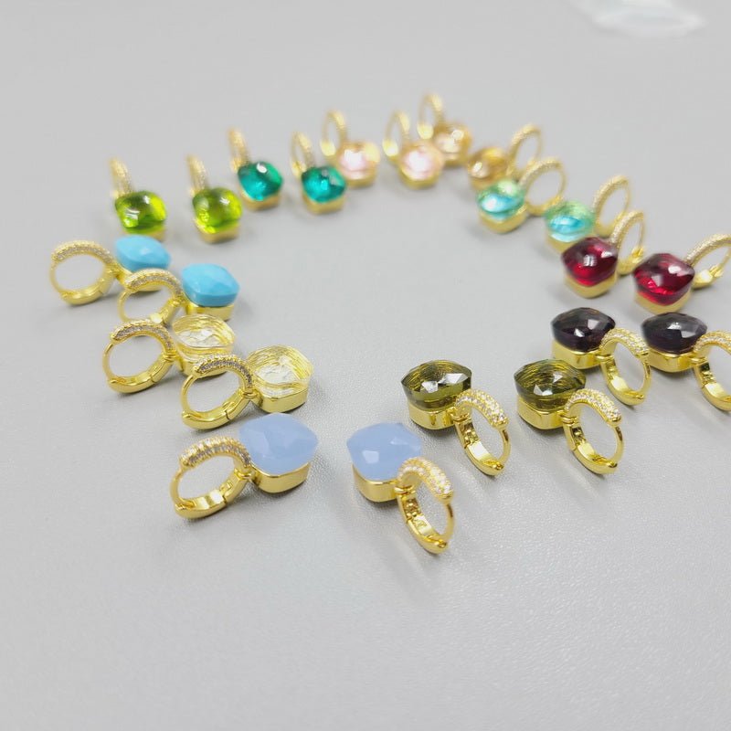 A semicircle of DiamondVeneer Fashion Zirconite Cabochon Hoop Huggies Earrings (827E100G), each accented with a different colored cabochon in blue, green, yellow, pink, and red, displayed on a light gray surface.