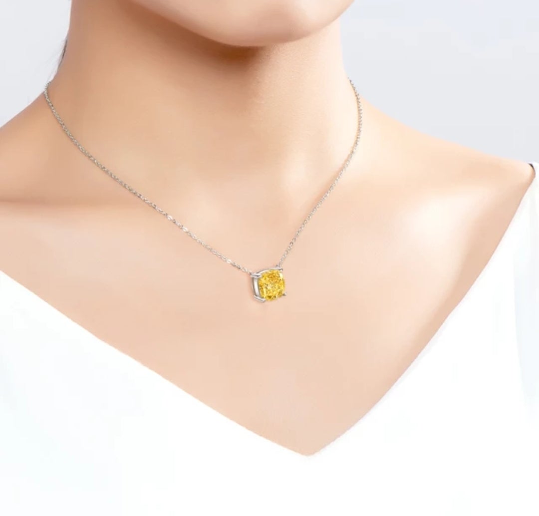 A close-up of a person wearing DiamondVeneer Fashion’s Cushion Square Cubic Zirconia 14K gold Solitaire Pendant (635P208K) with a yellow gemstone, set against a white top and neutral background.