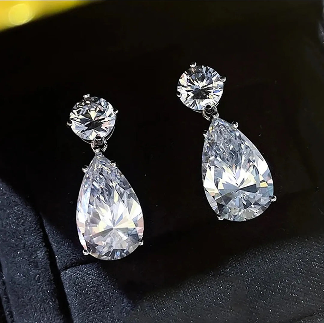 Woman in checkered blazer with wet, wavy hair wears Zirconmania Pear Drop Cubic Zirconia Earrings—distinctive sparkle and elegance.