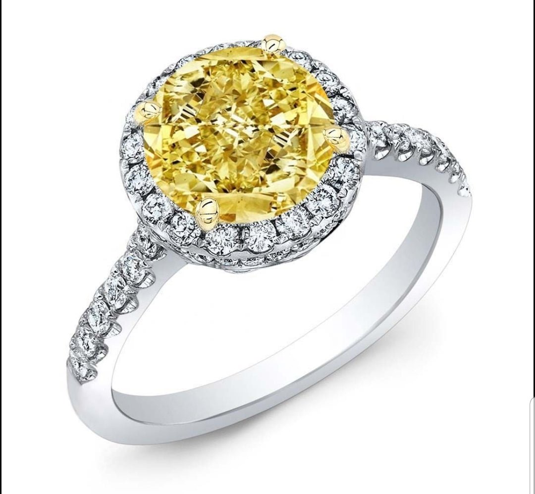 The DiamondVeneer Fashion Round Cubic Zirconia Halo Engagement Ring 800R70/2 in white gold features a large yellow stone surrounded by dazzling cubic zirconia and additional stones along the band for enhanced brilliance.