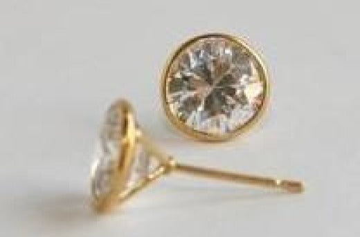 ZirconMania Fashion’s Wire Bezel Martini set Stud Earrings (PWIRE) feature sparkling round cubic zirconia stones in gold settings, elegantly displayed on a light surface.
