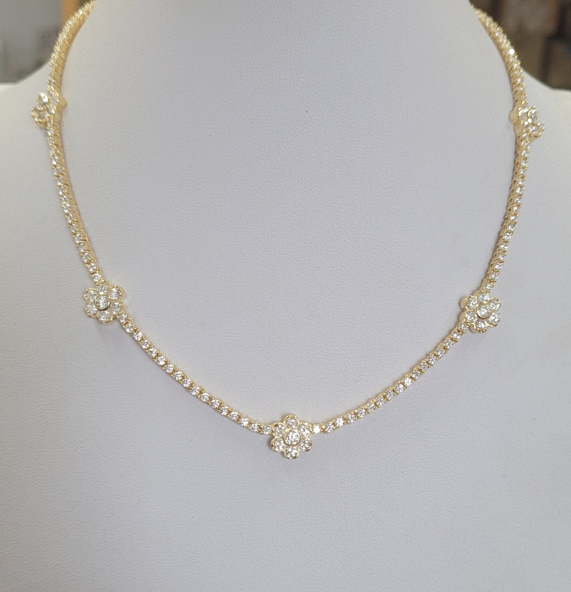 The Zirconmania Fashion Jewelry Cubic Zirconia Stations Tennis Necklace (Zirconite.501N11255) features sparkling cubic zirconia flower clusters on a platinum finish chain, beautifully displayed on a white jewelry bust.