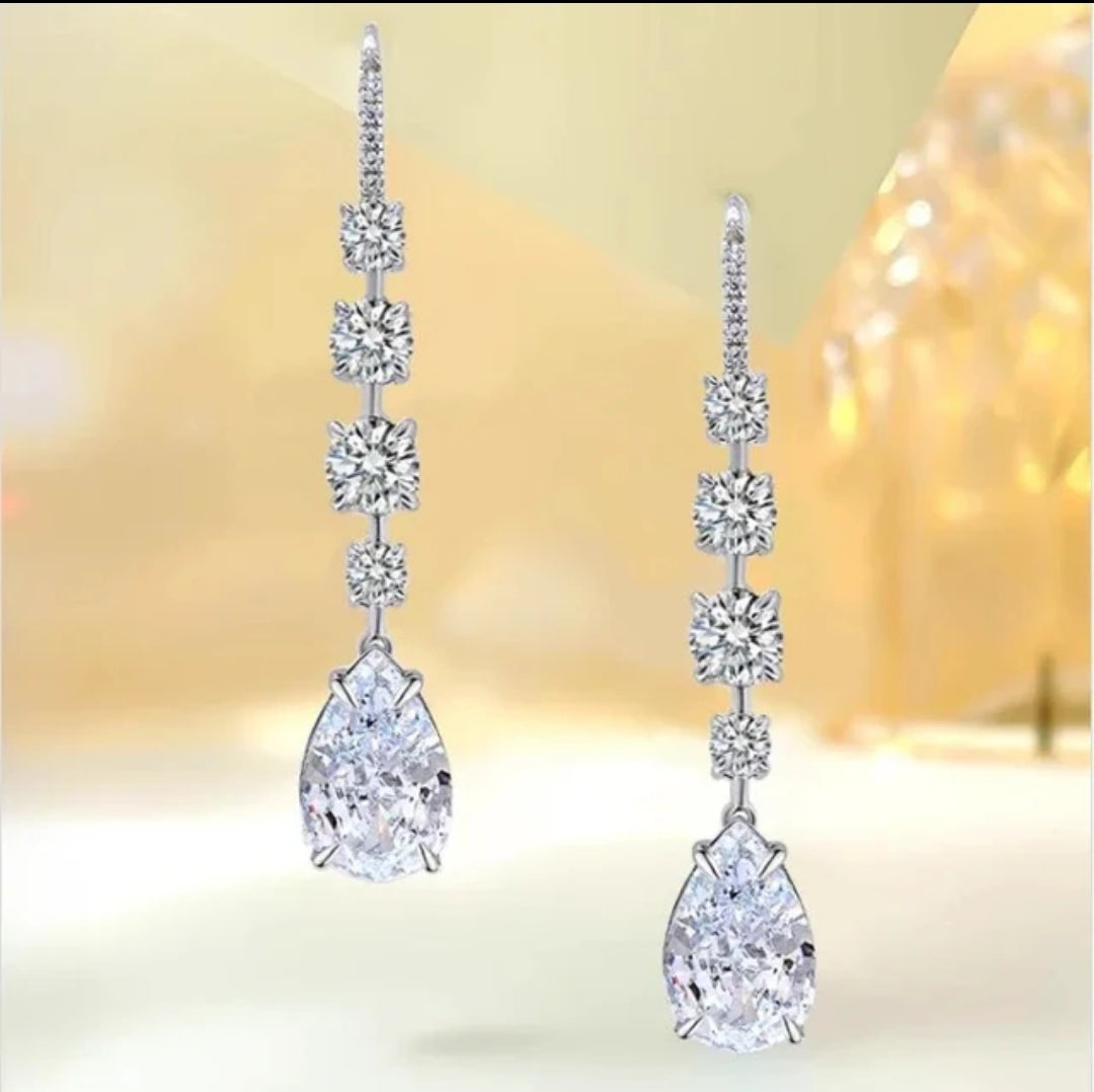 Silver drop earrings with two square and one teardrop clear gemstones in a vertical line, elegant jewelry displayed on white background.