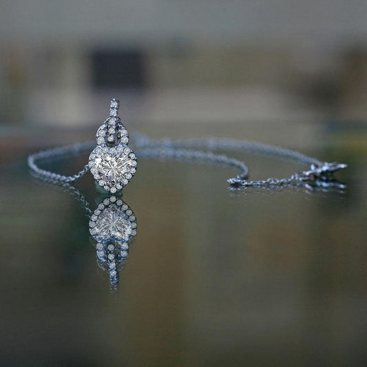 The DiamondVeneer Fashion 1CT Heart Diamond Veneer Cubic Zirconia Pendant (635P10779A) features a heart-shaped cubic zirconia set on a delicate chain, sparkling elegantly as it rests on a reflective surface.