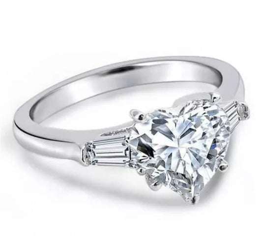 The DiamondVeneer Fashion 5CT Heart Cubic Zirconia Ring (635R71352) features a platinum-plated band with a large heart-shaped center stone and tapered baguette accents, displayed against a white background.
