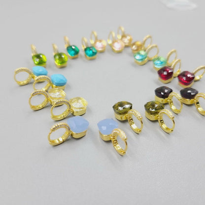 A semicircle of DiamondVeneer Fashion Zirconite Cabochon Hoop Huggies Earrings (827E100G), each accented with a different colored cabochon in blue, green, yellow, pink, and red, displayed on a light gray surface.