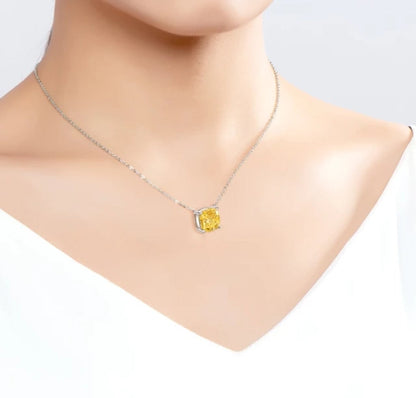 A close-up of a person wearing DiamondVeneer Fashion’s Cushion Square Cubic Zirconia 14K gold Solitaire Pendant (635P208K) with a yellow gemstone, set against a white top and neutral background.