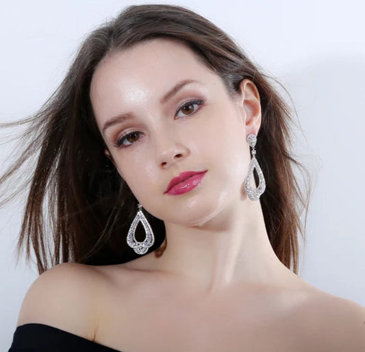 A woman with long brown hair in off-the-shoulder black attire poses against a white background, highlighting DiamondVeneer Fashion Cubic Zirconia statement Earrings Zirconite 698E3365. She wears glossy pink lips and subtle eye shadow.