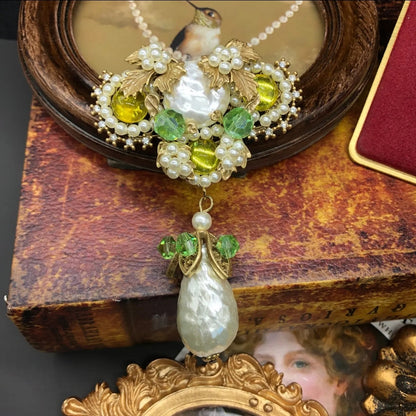 Decorative brooch with Baroque pearls, yellow and green gemstones on a white background