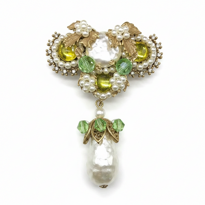 Decorative brooch with Baroque pearls, yellow and green gemstones on a white background