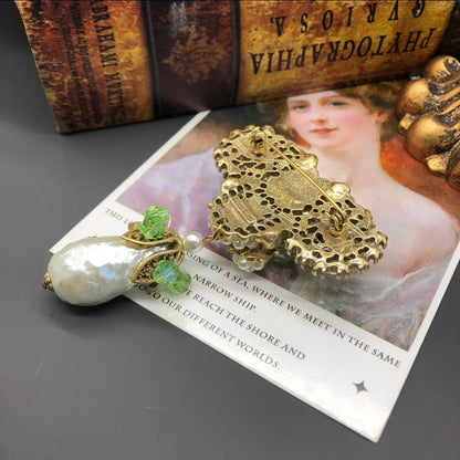 Back of Decorative brooch with Baroque pearls, yellow and green gemstones on a white background
