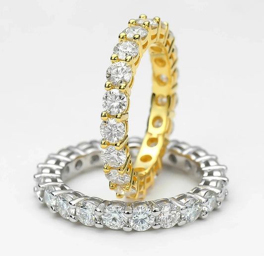 Two eternity rings are pictured: one has a gold band with large round gemstones, while the other is a DiamondVeneer Fashion Eternity Band Ring (model 635R103), featuring sterling silver and sparkling cubic zirconia stones.