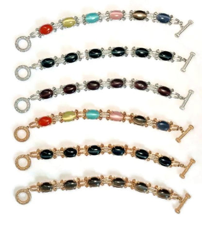 Five DiamondVeneer Fashion Cats Eye Oval Cabochon set w/Zirconite Cubic Zirconia Bracelet 501B097 pieces are arranged in parallel on a white background, each with metal links, toggle clasps, and one 18K Gold option.