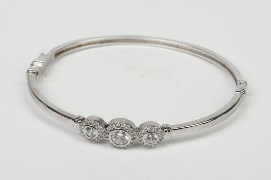 The DiamondVeneer Fashion Hinged Zirconite Cubic Zirconia 3-Stones Bezel Rhodium Bangle Bracelet.698B003, featuring three clear stones with sparkling accents, is showcased on a plain white background.
