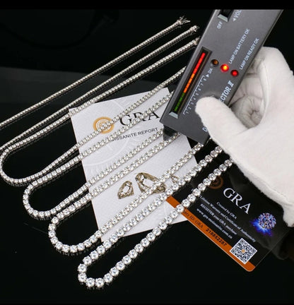 A gloved hand uses a diamond tester on the DiamondVeneer Fashion Moissanite Lab Created Diamond Tennis Necklace (850N4MM), shown with GRA certification, authenticity card, and other jewelry—an elegant diamond alternative on glossy black.
