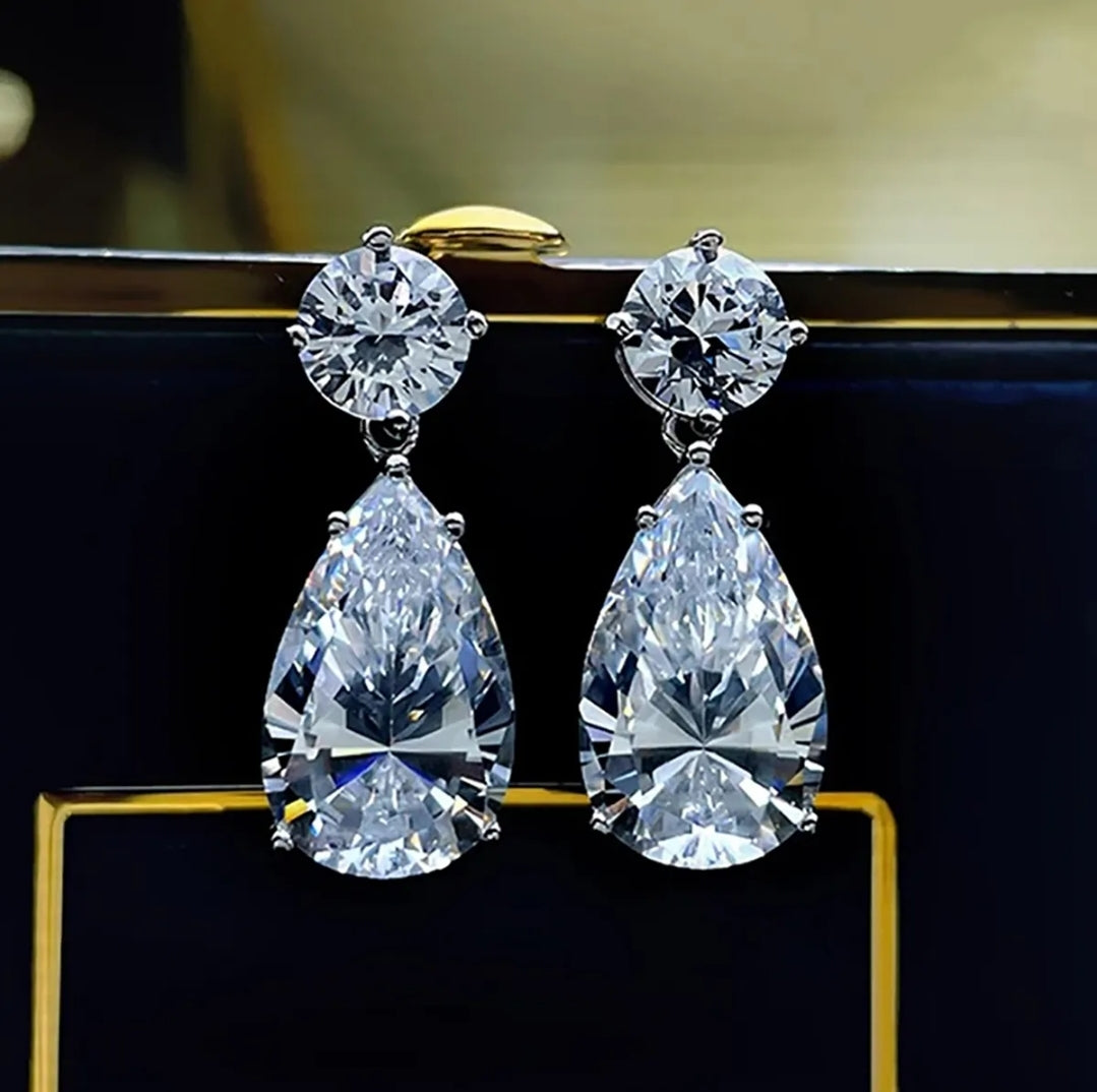 Woman with wet wavy hair in plaid blazer models Zirconmania pear drop cubic zirconia earrings against plain light background.