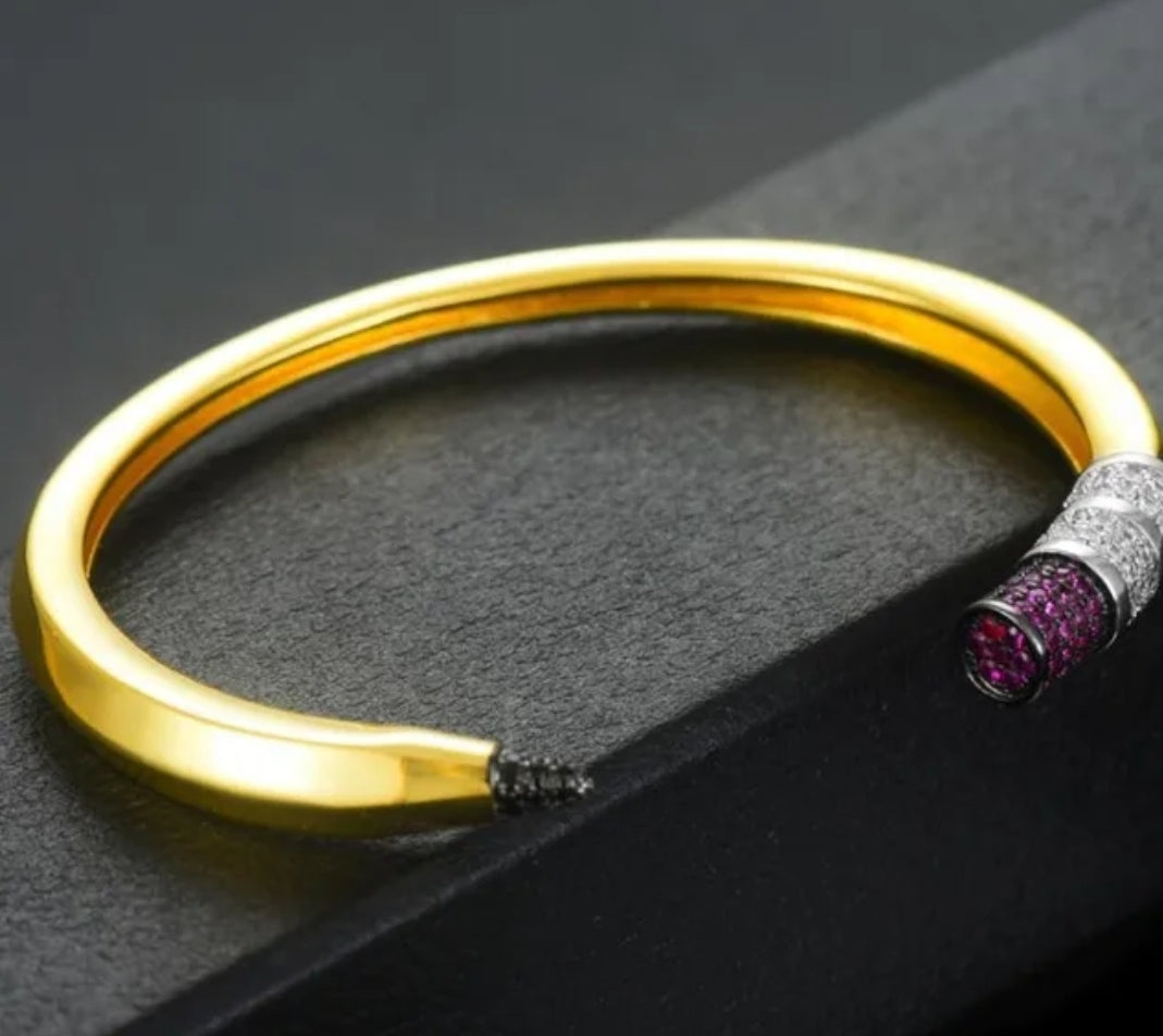 The zirconmania fashion jewelry Pencil Bangle Bracelet Cuff (843B100) features a gold adjustable design with black, silver, and pink-purple cubic zirconia accents—the perfect teacher gift.