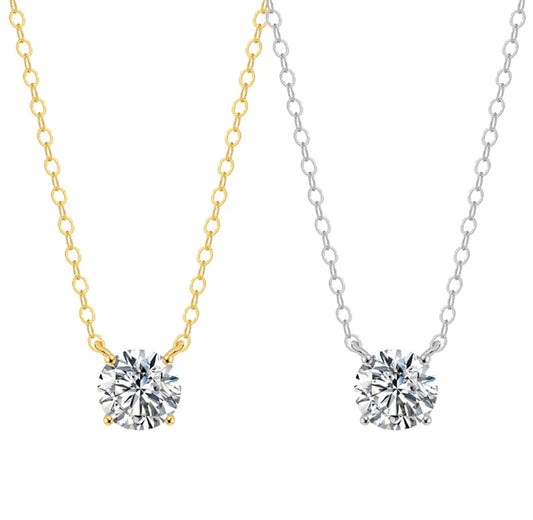 Two Diamond Veneer Jewelry necklaces feature round cubic zirconia solitaire pendants—one set on a 14K gold chain and the other on silver—each in a simple, elegant setting. Product: 14K Gold Round Cubic Zirconia Solitaire Pendant, 635P100Mk.