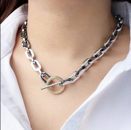 A person wears the Unisex Paper Clip Link Chain Necklace Zirconite (856N101) by Zirconmania Fashion Jewelry—featuring large rectangular stainless steel links and a gold toggle clasp—styled with a white collared shirt.