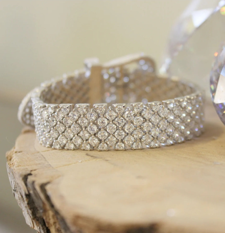 Wide pink cubic zirconia buckle bracelet by Zirconmania, sparkling with crystals, stands out on wood for its bold, luxe design.