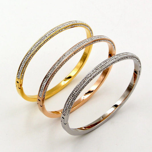 The DiamondVeneer Fashion Zirconite Stainless Steel hinged Bangle Bracelet 709B11, shown in gold, rose gold, and silver tones with sparkling crystal rows, is displayed side by side on a plain white background.