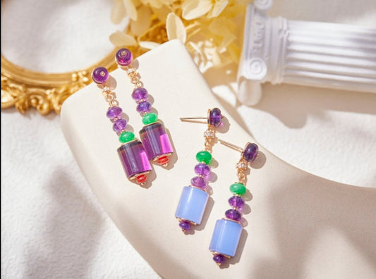 DiamondVeneer Fashions Cabochon Gems Beads Zirconite Cubic Zirconia Earrings 840E100, featuring purple, green, and blue beads, are displayed on a curved cream surface with a gold frame and white column in the background.