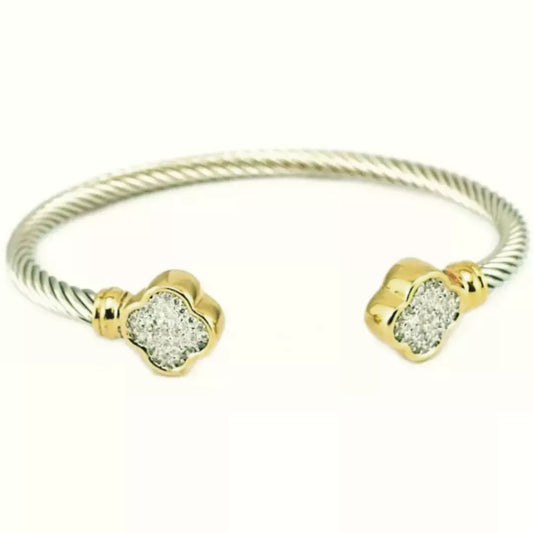 The DiamondVeneer Fashion Zirconite twisted cable open Bangle Bracelet (655B33) features gold-toned ends with designer-inspired clover shapes, each encrusted with sparkling stones.