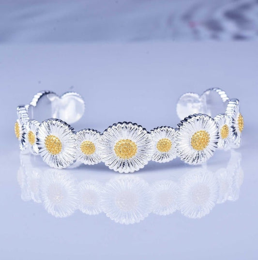 The DiamondVeneer Fashion Zirconite inspired Italian Sunflower satin open Bangle (831B101) with a two-tone finish is displayed on a reflective surface.