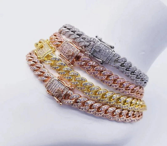 The DiamondVeneer Fashion Cuban Cubic Zirconia Pave Curved Link Bracelet, Zirconite 818B, shines in silver, gold, and rose gold tones with sparkling stones—stacked for a bold hip-hop style on a white mannequin wrist.
