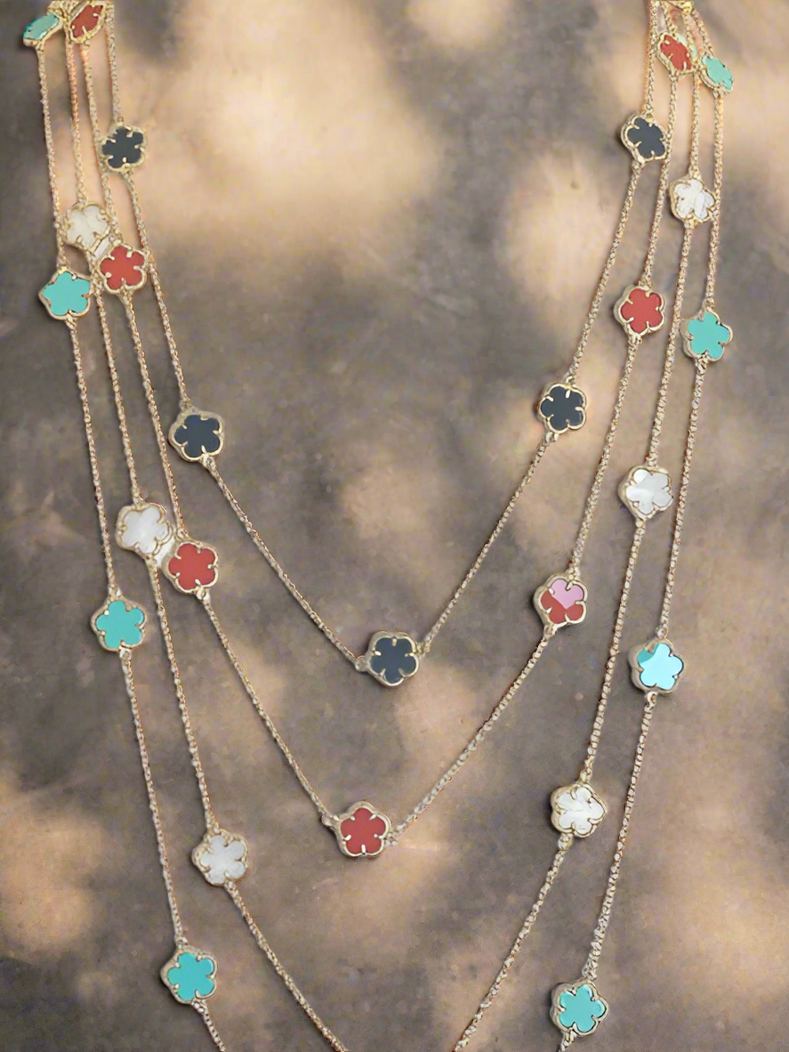 The Necklace Clover Stations Long Zirconite Necklace by Zirconmania Fashion Jewelry features four-leaf clover-shaped charms in turquoise, black, red, and white, shown against a softly lit neutral background.