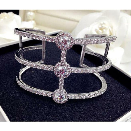 The DiamondVeneer Fashion Open Ends Zirconite Cubic Zirconia Rhodium Bangle Bracelet (698B2094) features three sparkling parallel bands with clear crystals and three round central gems, beautifully presented in a jewelry box.