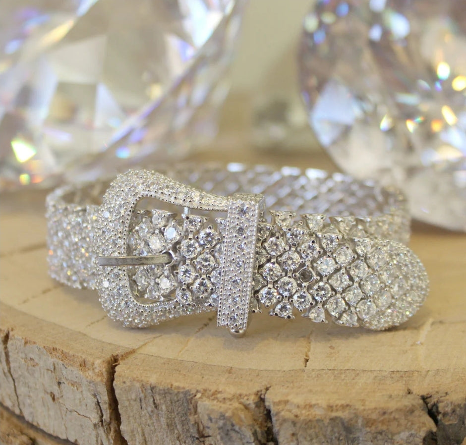 Wide pink cubic zirconia buckle bracelet by Zirconmania, sparkling with crystals, stands out on wood for its bold, luxe design.