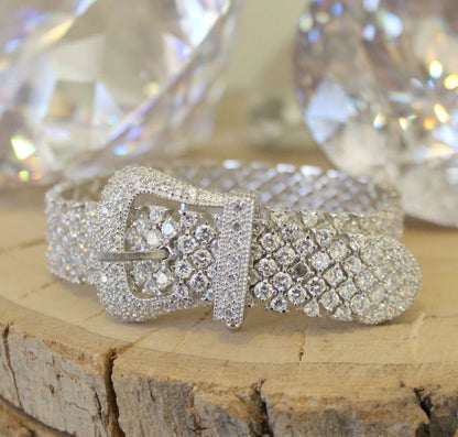 Wide pink cubic zirconia buckle bracelet by Zirconmania, sparkling with crystals, stands out on wood for its bold, luxe design.