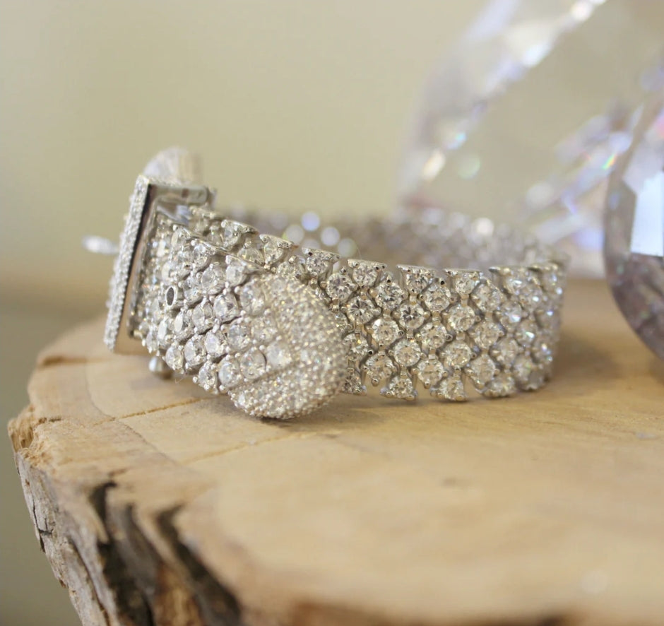 Wide pink cubic zirconia buckle bracelet by Zirconmania, sparkling with crystals, stands out on wood for its bold, luxe design.