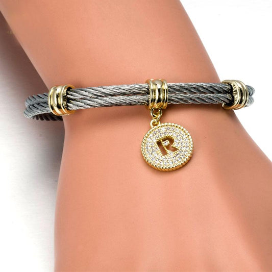The DiamondVeneer Fashion Stainless Steel Cable Monogram Initial Charm Bracelet/Bangle.500B4168 features gold accents, a round gold charm with clear stones and raised letter R, offering hypoallergenic elegance for everyday wear.