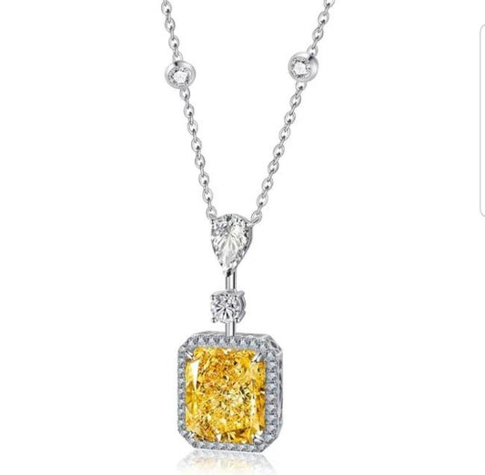 The Radiant Diamond Veneer Cubic Zirconia Halo Pendant Necklace by DiamondVeneer Fashion (800P101) showcases a large square yellow center stone, haloed by sparkling CZ, with two round and one teardrop-shaped clear stones on a delicate chain.